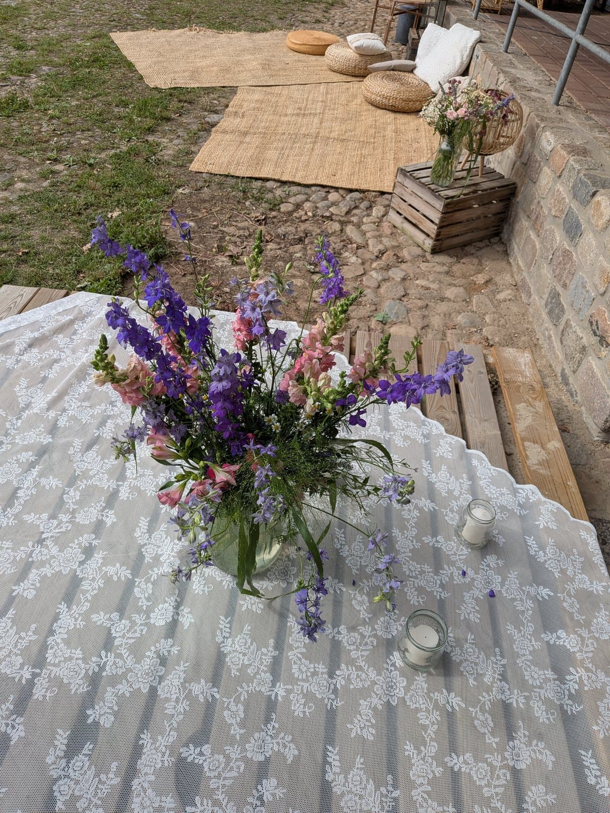 Gedeckte Tische im Freien mit weißer Spitzendecke und Wiesenblumen