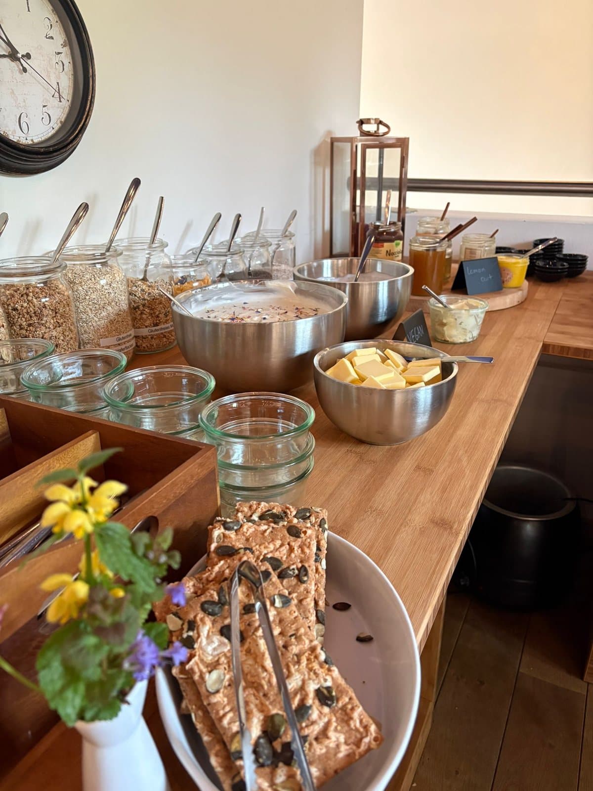Frühstücksbuffet mit Müsli in Gläsern, Aufstrichen und Blumen