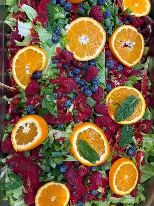 Bunte Salatplatte mit Beeren, Orangen und Blüten