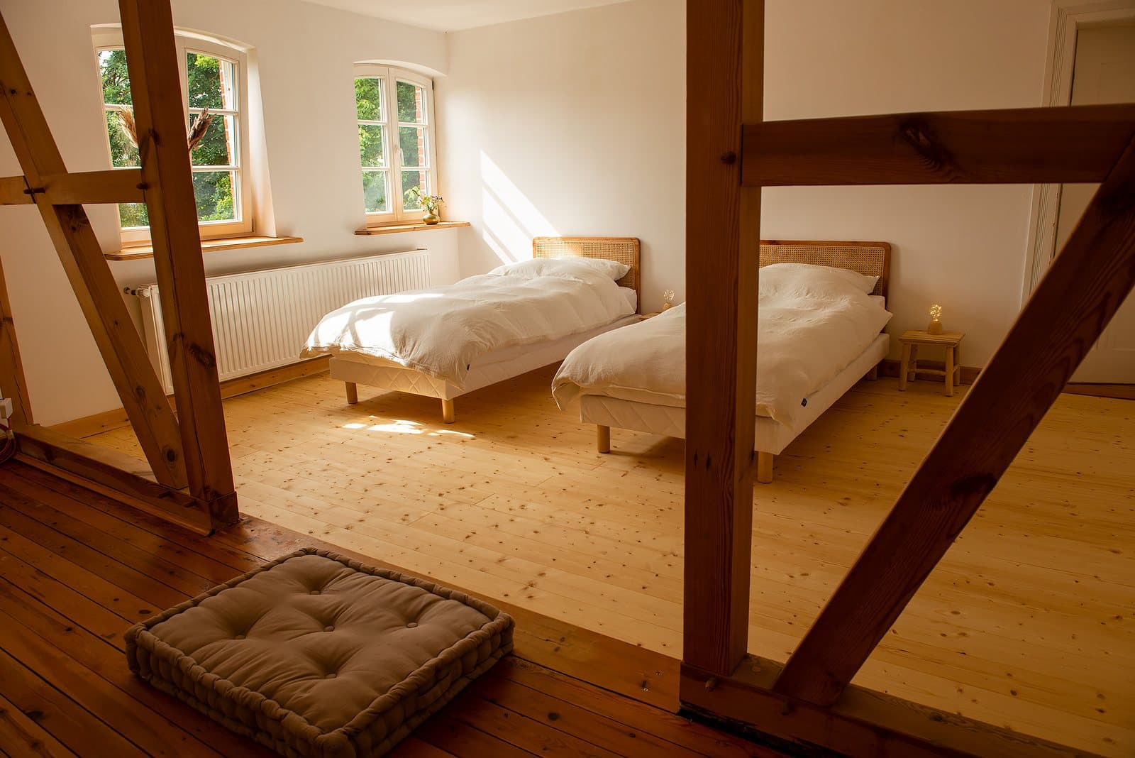 Schlafzimmer mit zwei Betten unter altem Fachwerk